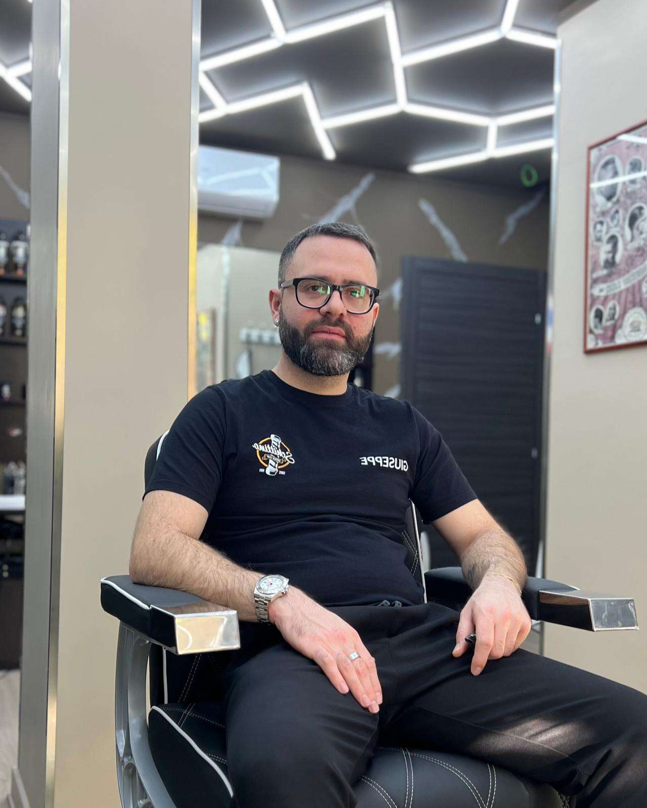 Giuseppe Schittino, titolare di Schittino Barber Shop, seduto su una poltrona da barbiere